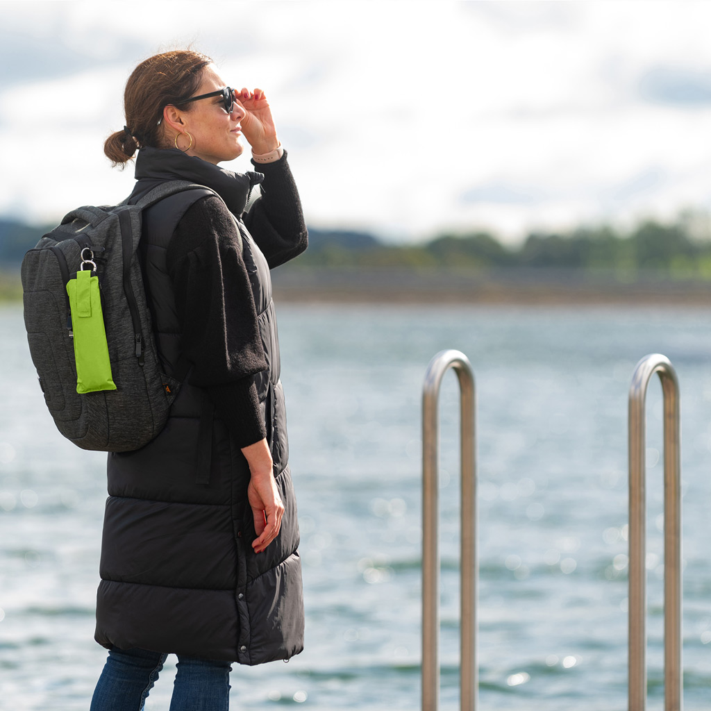 Woman on the jetty with backpack and pocket umbrella