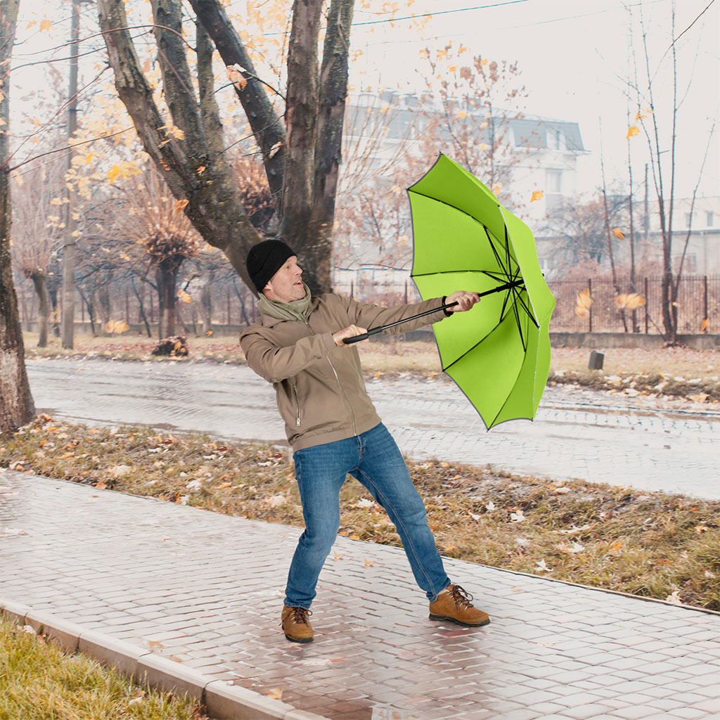Mann mit Schirm im Wind, Sturm und Regen