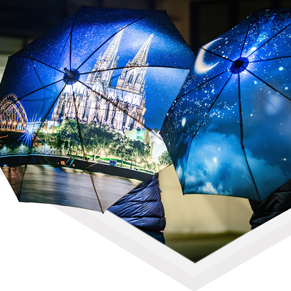 Two allover xpress umbrella next to each other hold by people