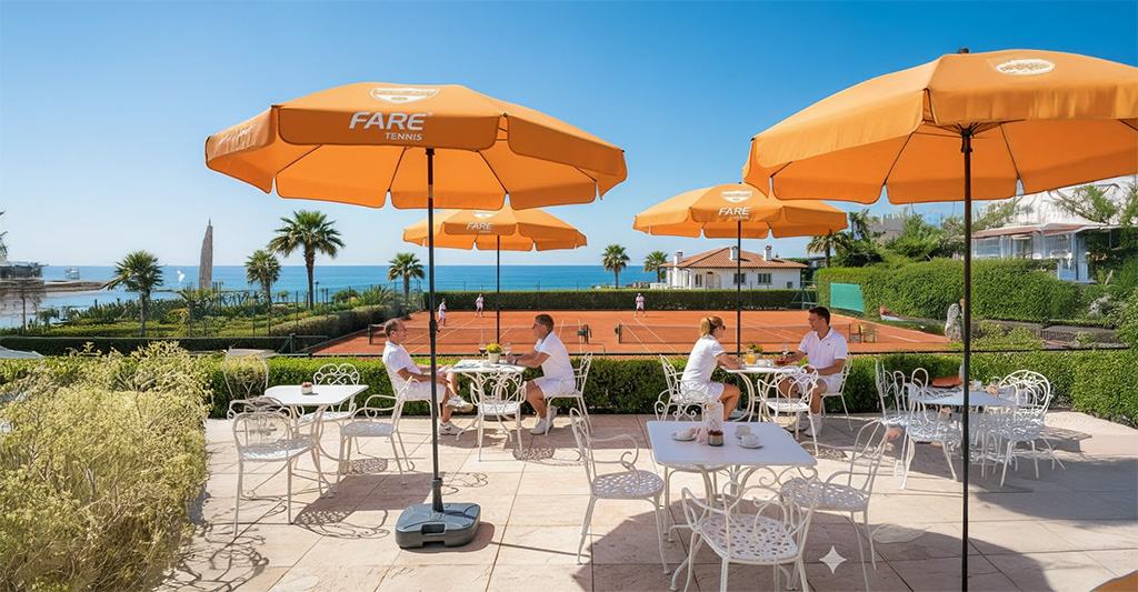 Oranger FARE Sonnenschirm auf der Terrasse eines Tennis-Resorts mit Meerblick.
