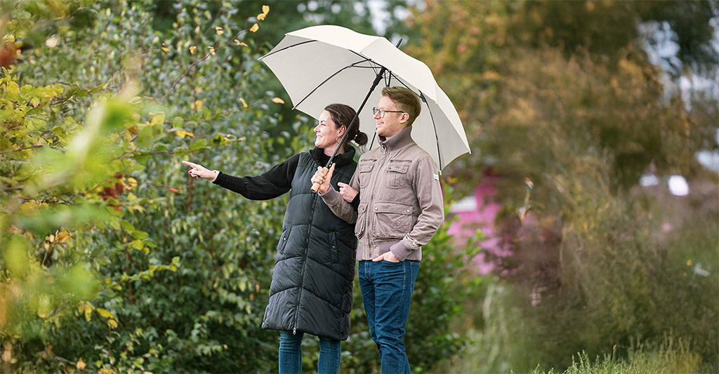 Paar unter einem gemeinsamen Gaesteschirm im Park