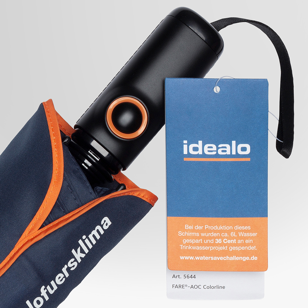 Nahaufnahme eines dunkelblauen Taschenschirms mit orangefarbener Einfassung und schwarzem Griff mit orangefarbenem Akzent. Am Griff hängt ein blau-oranges Hangtag mit idealo-Logo und Produktinformationen.