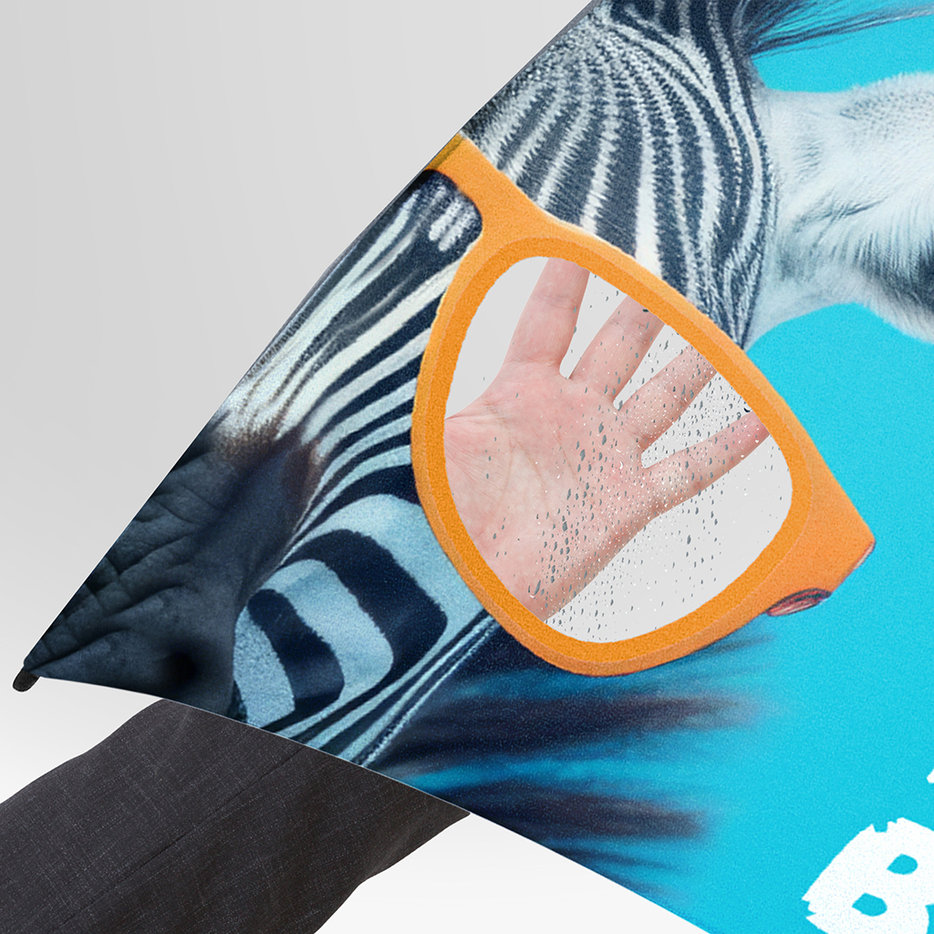 An umbrella featuring a customised eyewear design in blue, with a transparent window in the cover. A hand can be seen through the window, whilst raindrops on the surface emphasise the weather conditions.
