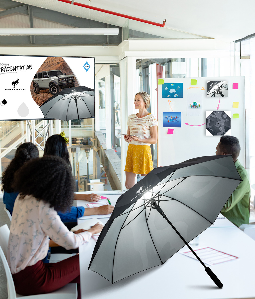 Büro in dem Personen etwas präsentiert wird, Schirms steht auf dem Tisch