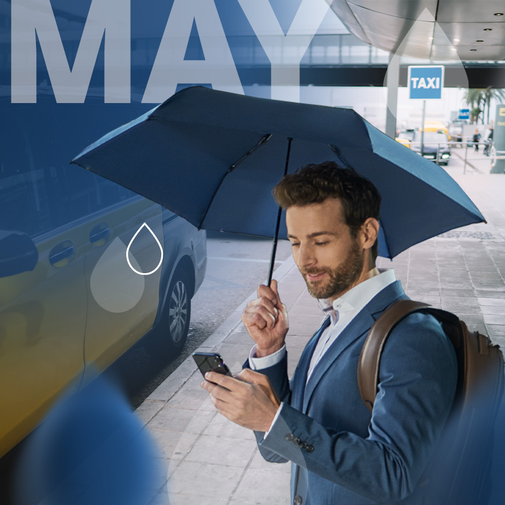 Umbrella of the month May: Man at a taxi rank, waiting with a navy-coloured umbrella in his hand. Text: May