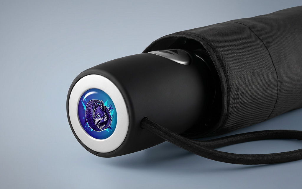 A close-up of the handle of a pocket umbrella featuring a purple and blue doming sticker on the handle.